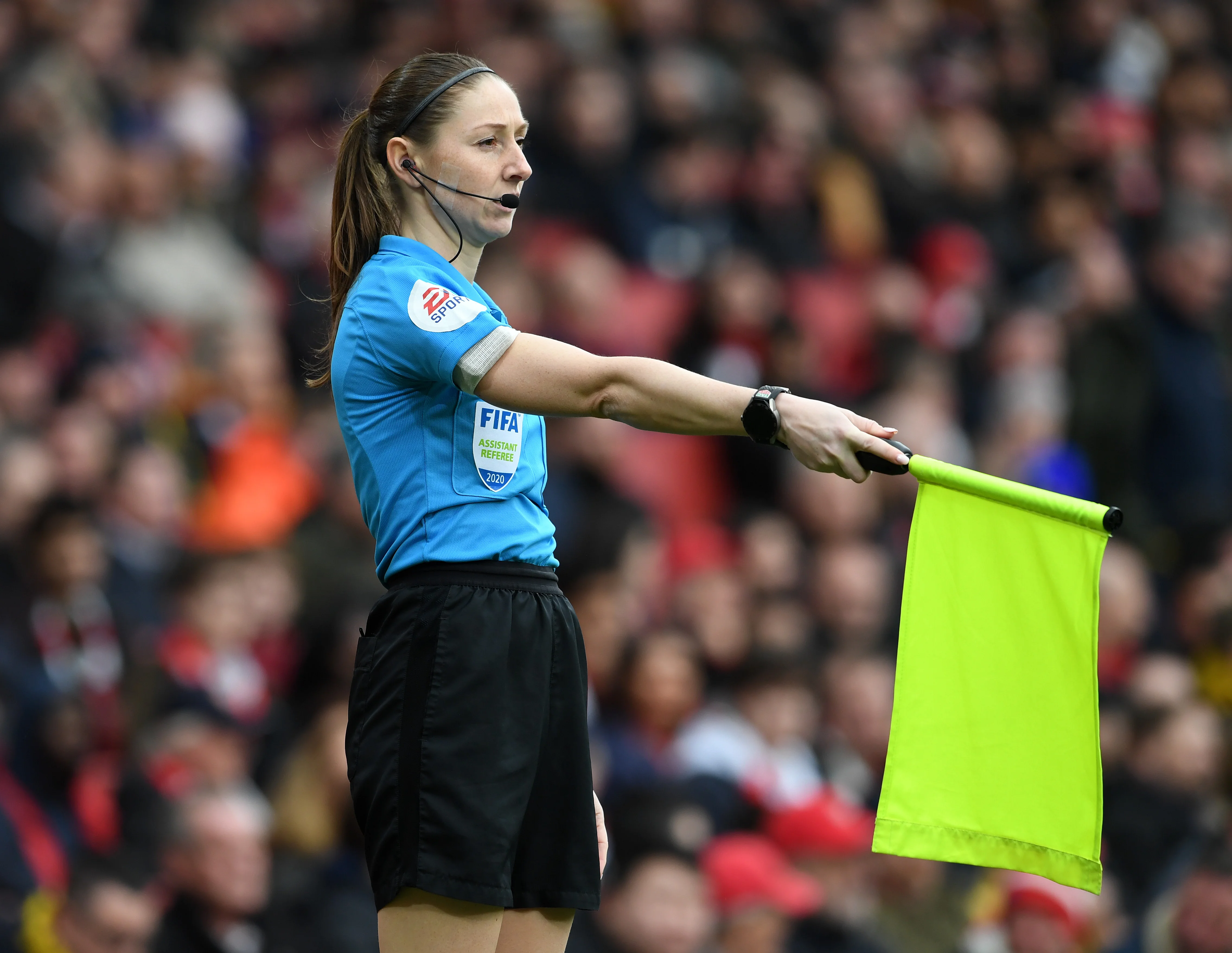 A Premier League assistant referee running along the touchline aligned with the second-to-last defender during open play