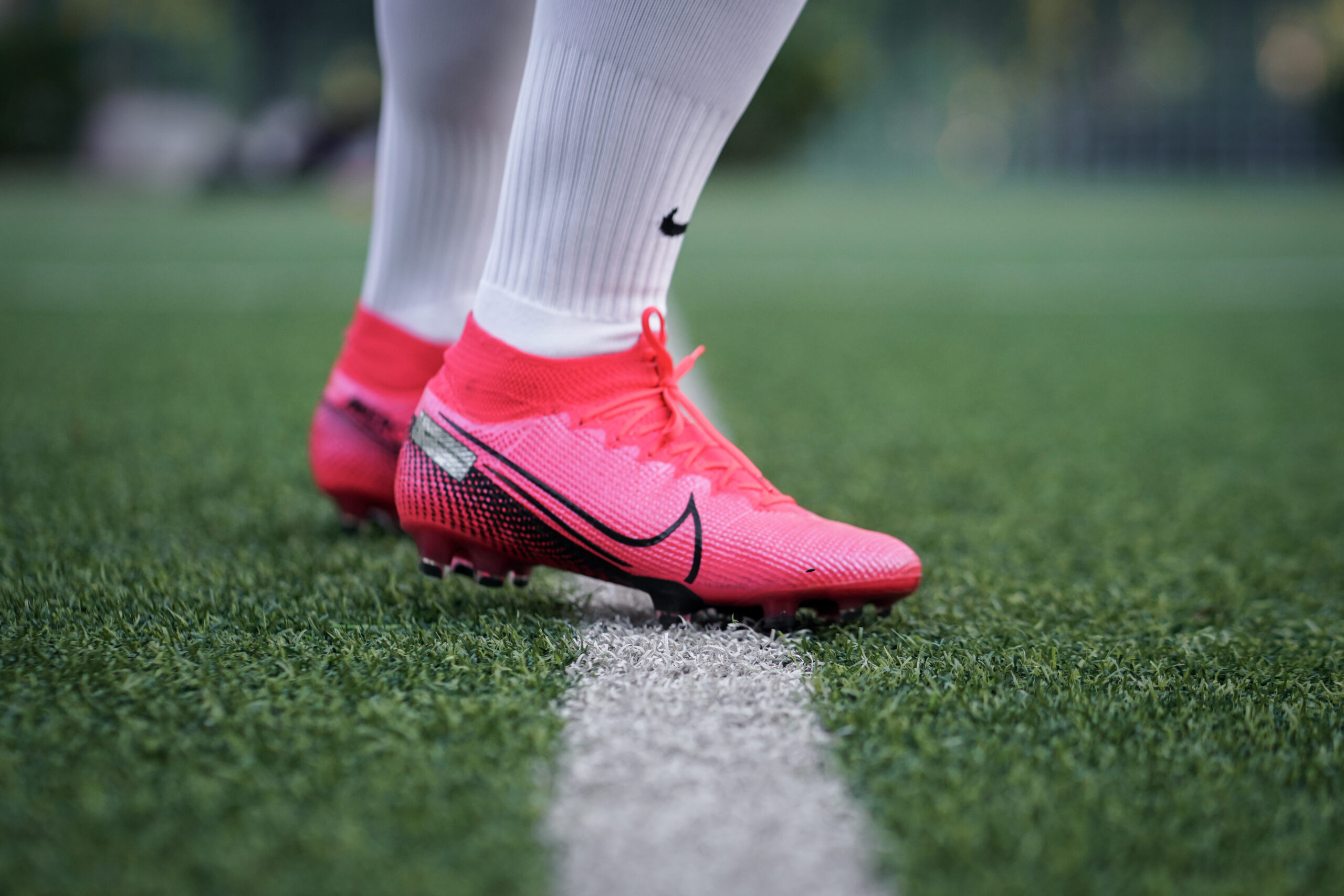 A close-up view of soccer cleats planted on an artificial turf field during warmups