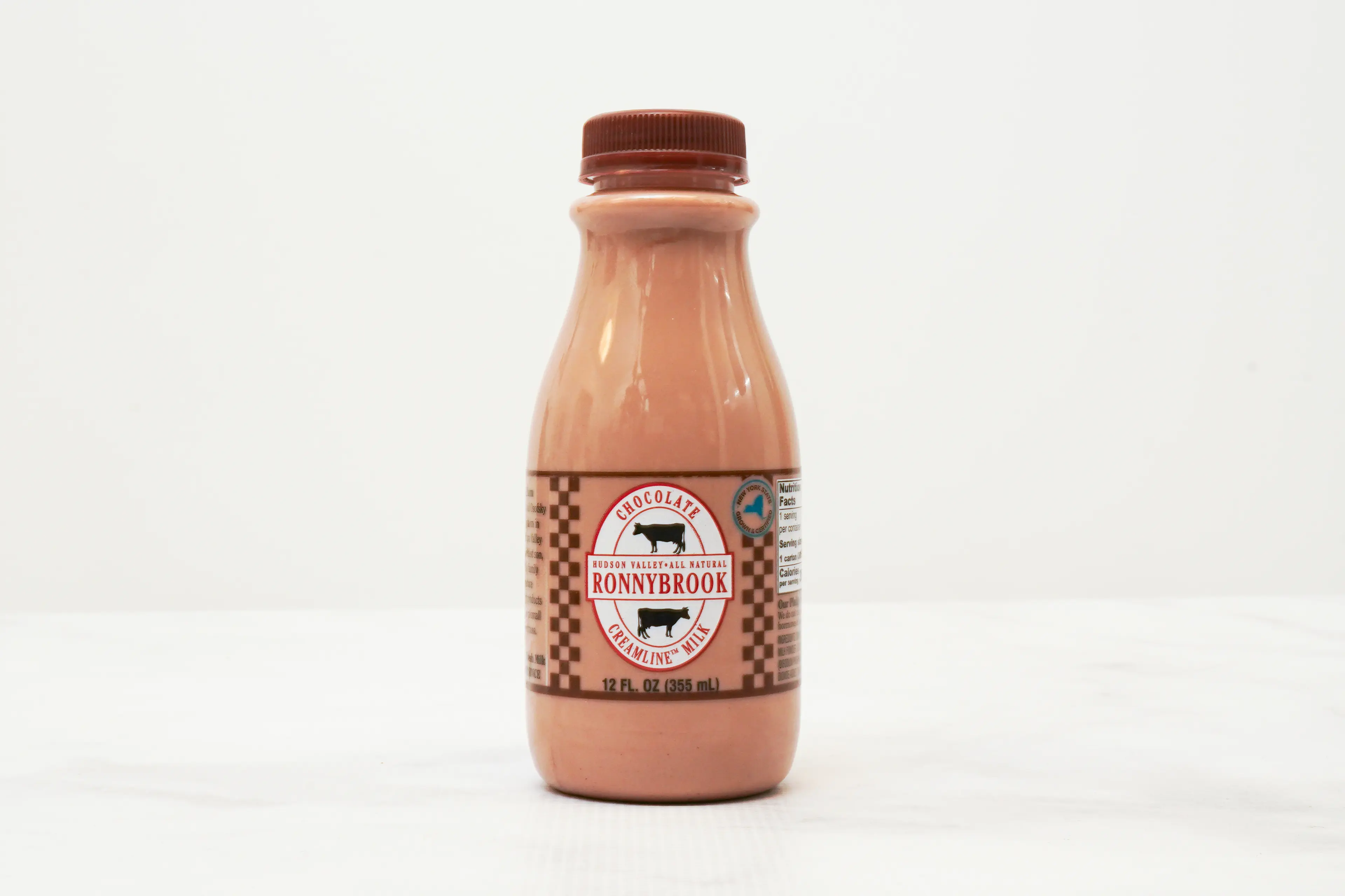 A cold bottle of chocolate milk on a locker room bench next to a pair of basketball shoes