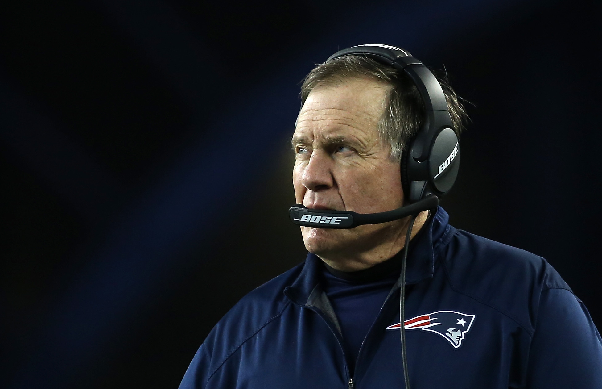 A football coach on the sideline wearing a headset during a close game.