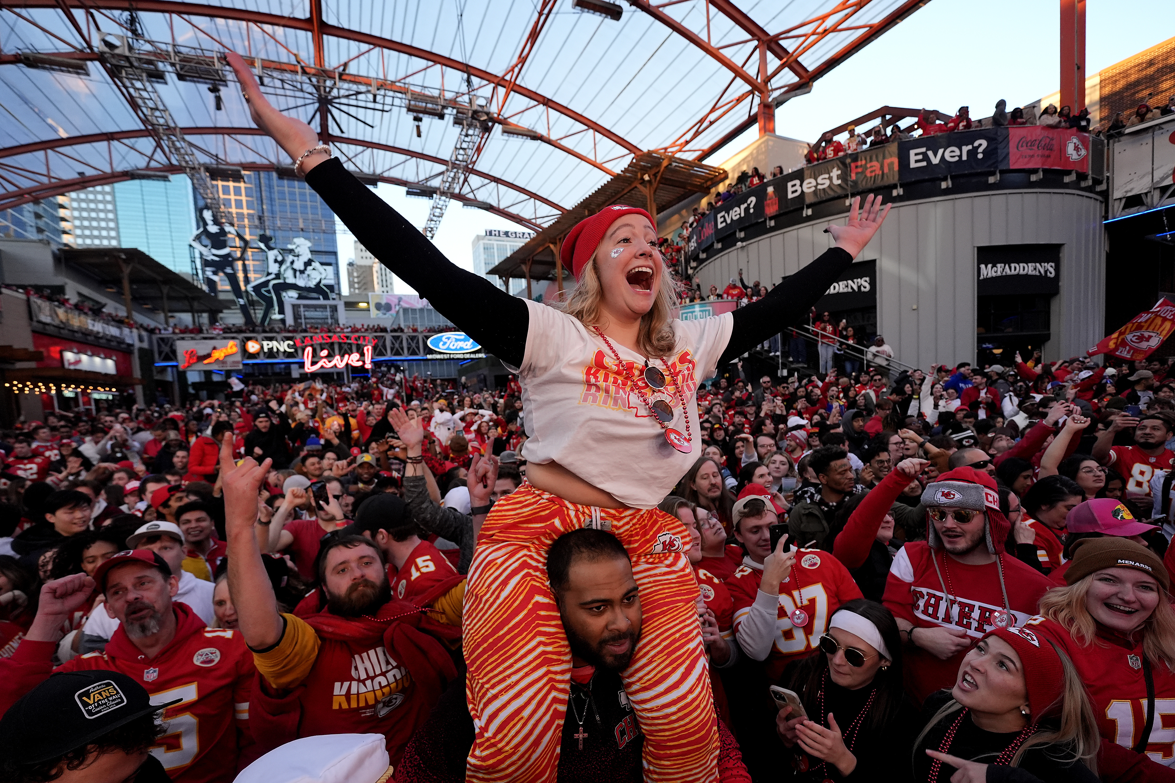 A group of friends watching a Sunday football game on a large TV with snacks on a coffee table during a casual watch party