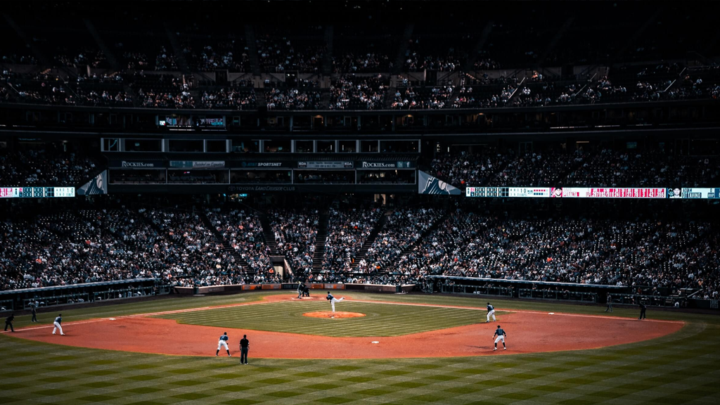 A packed MLB stadium during a night playoff game, with fans standing and rally towels raised
