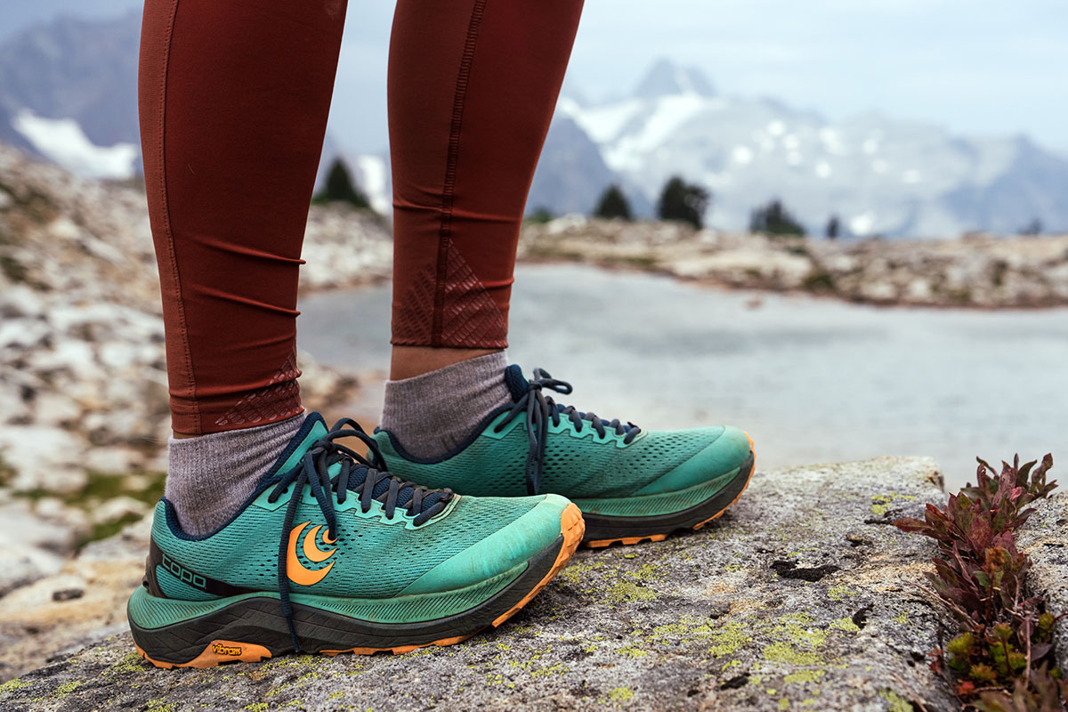 A pair of Topo Athletic Ultraventure trail shoes sitting on a rocky ridgeline, showing a wide toe box and protective midsole