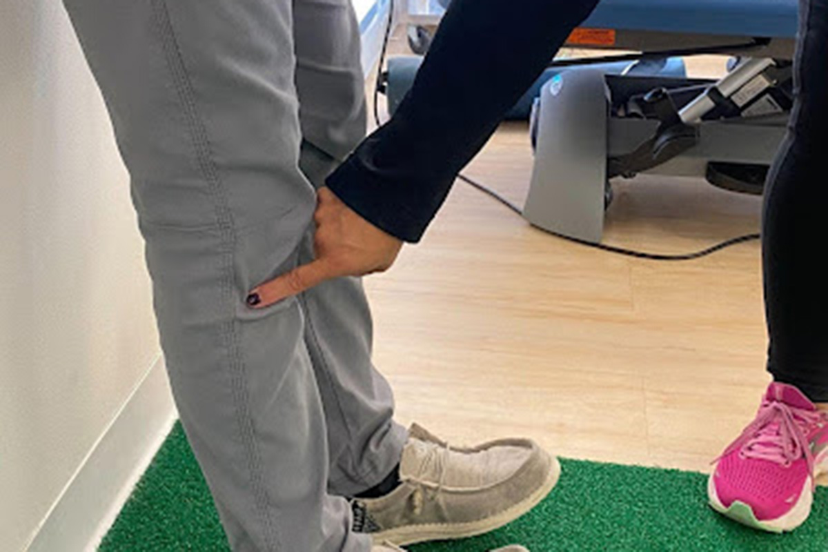 A physical therapist palpating and evaluating a runner’s lower leg while the athlete sits on a treatment table in a clinic