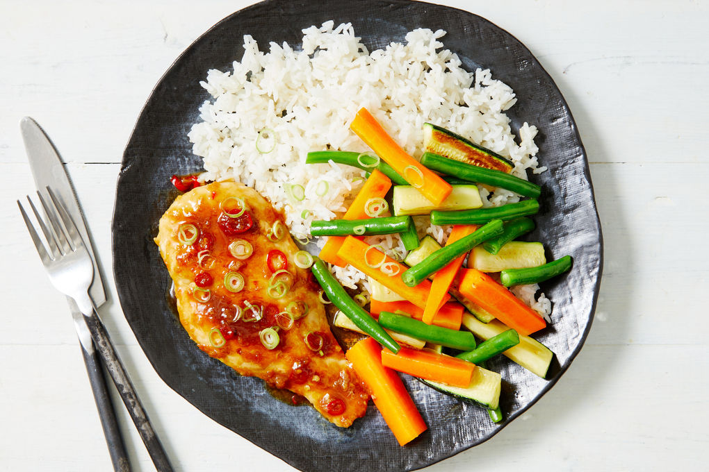 A simple post-workout meal with grilled chicken, rice, and vegetables on a plate on a kitchen table