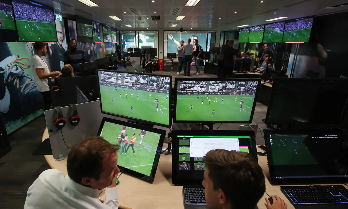 A team of video assistant referees sitting in a control room monitoring multiple live camera angles during a major European match