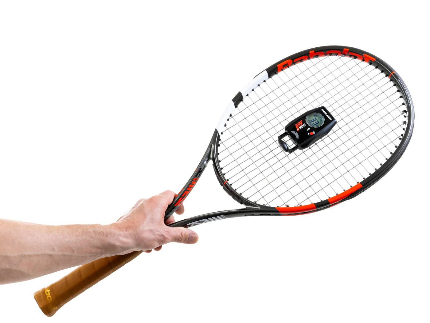 A tennis coach standing courtside holding a player’s tennis racket and checking the string bed with a focused expression