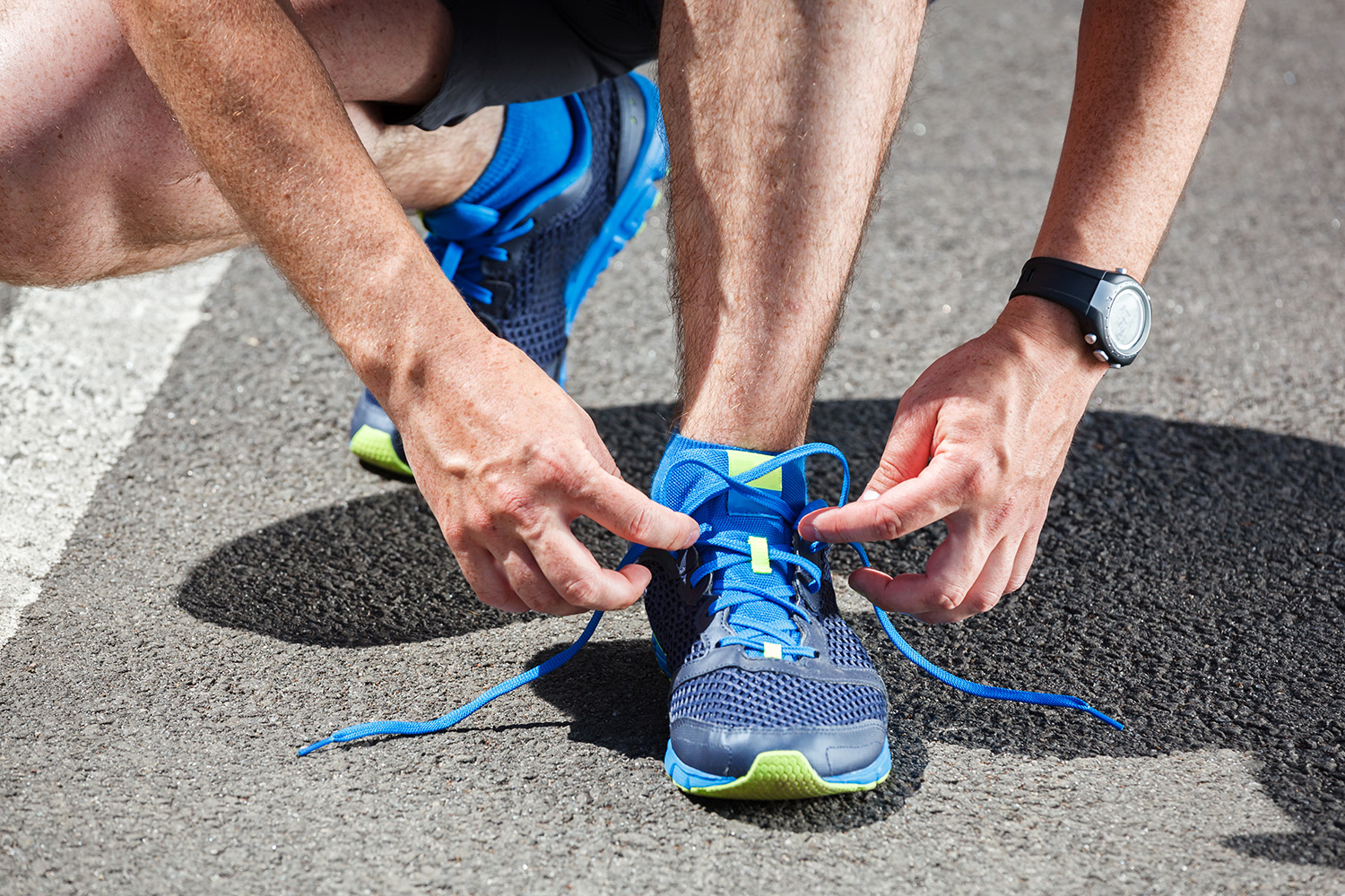 A triathlete slipping into running shoes in the transition area next to a bike rack during a race
