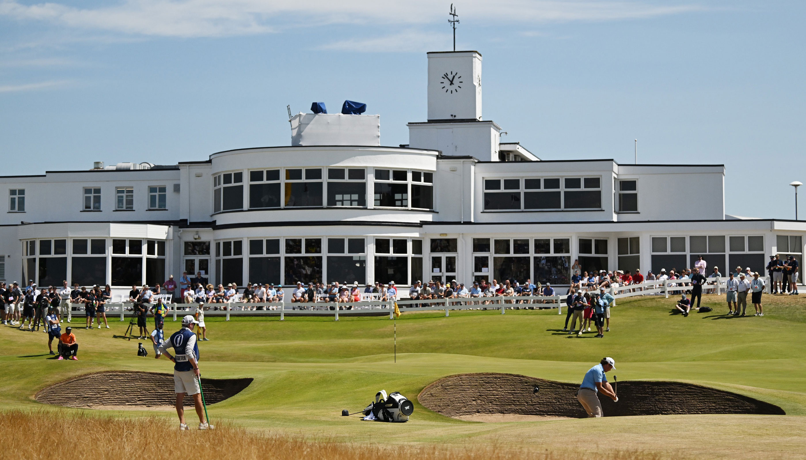 A wide fairway view at Royal Birkdale during The Open Championship in 2026 with grandstands, deep bunkers, and overcast seaside skies
