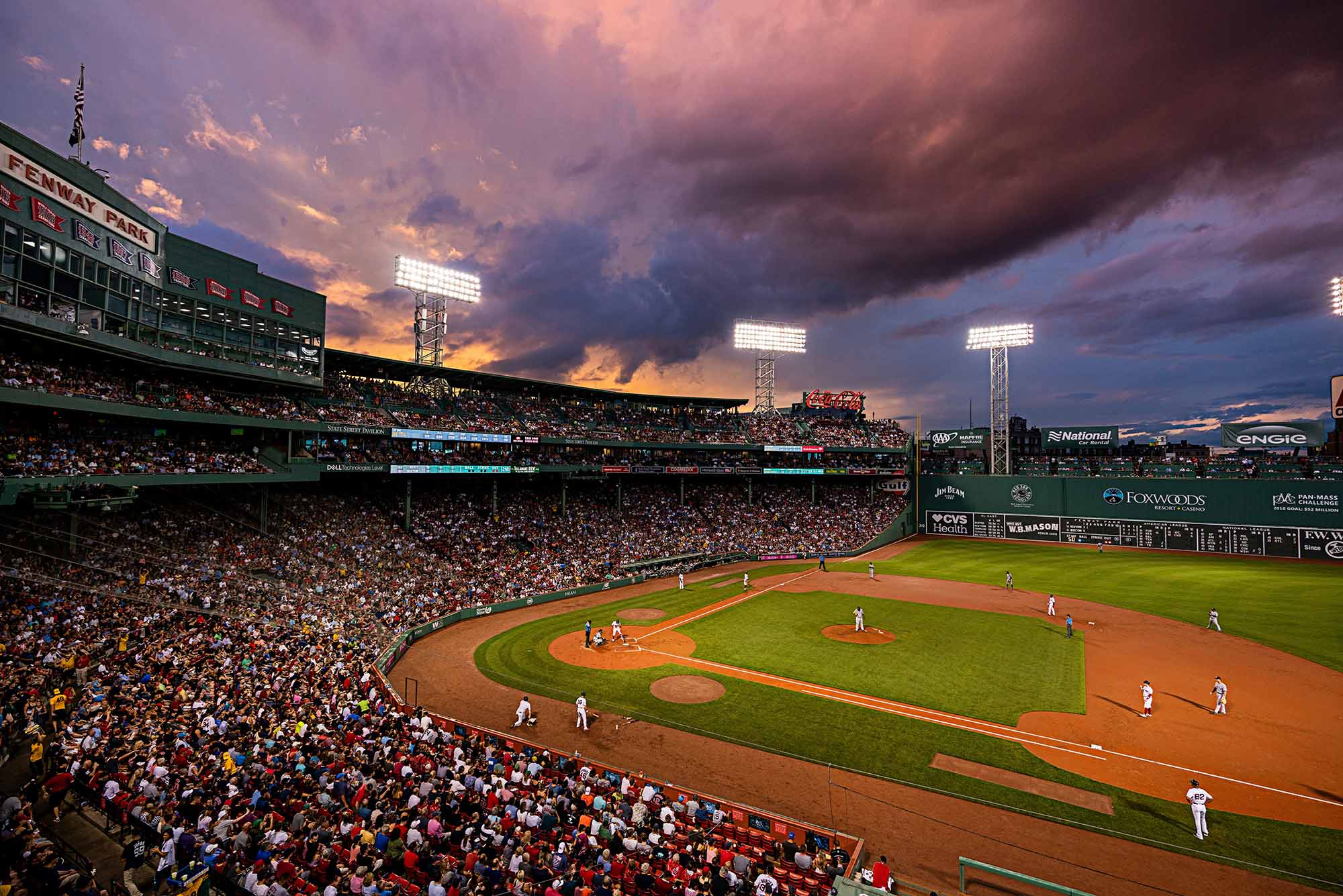A wide view of Fenway Park during a Red Sox home game at night, with the field lit under stadium lights and fans filling the stands