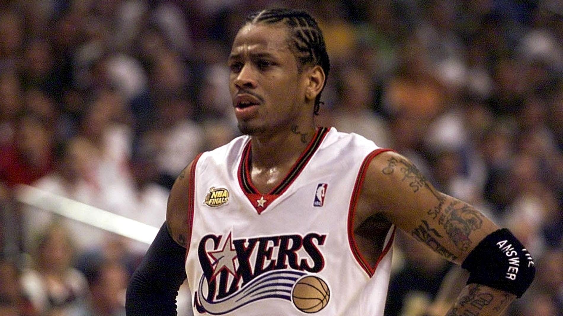 Allen Iverson smiling at a public basketball-related appearance, wearing casual streetwear, photographed in a candid moment