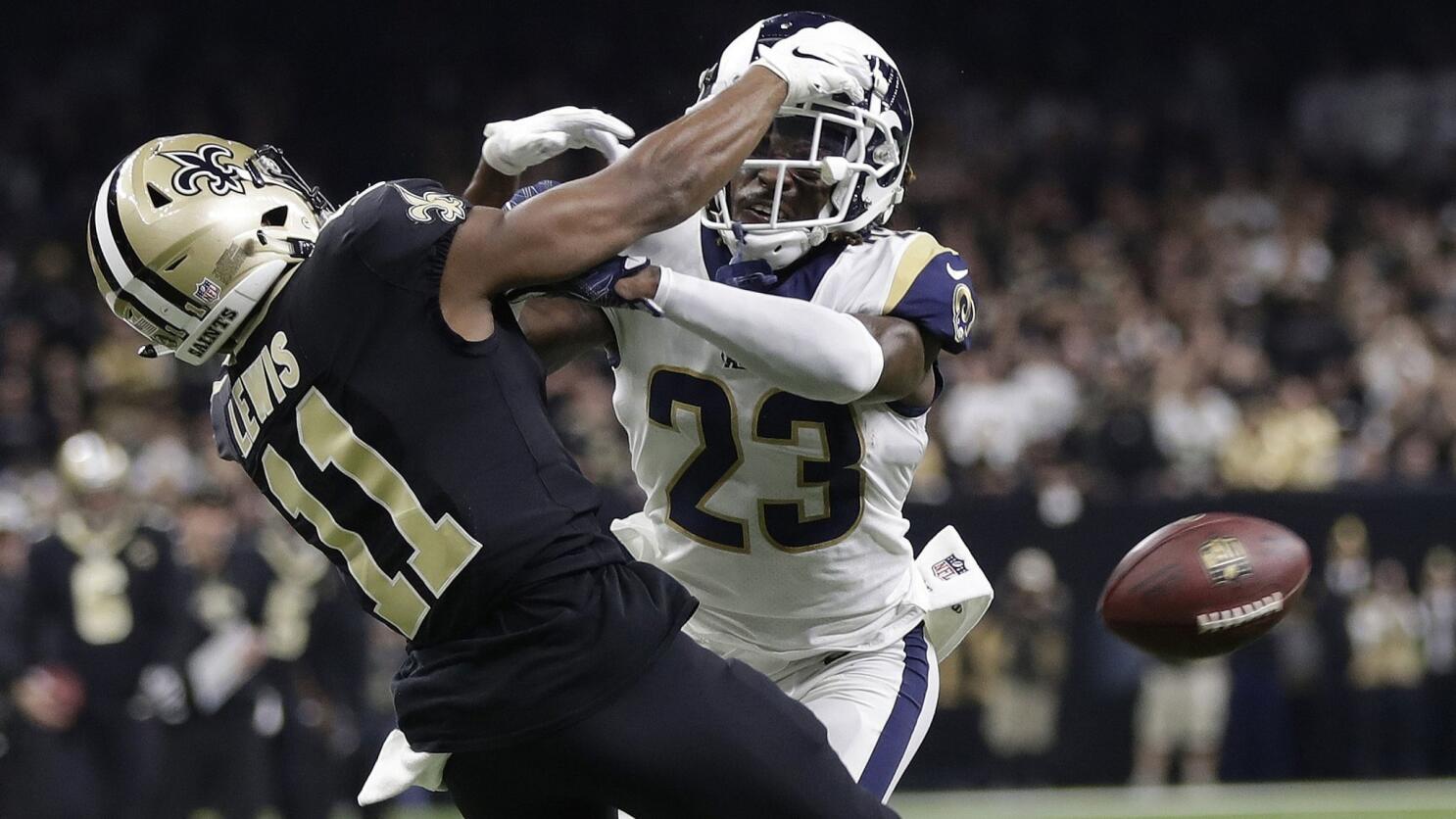 An NFL cornerback in tight coverage with his back to the quarterback as a receiver looks up for an incoming pass, game action photograph