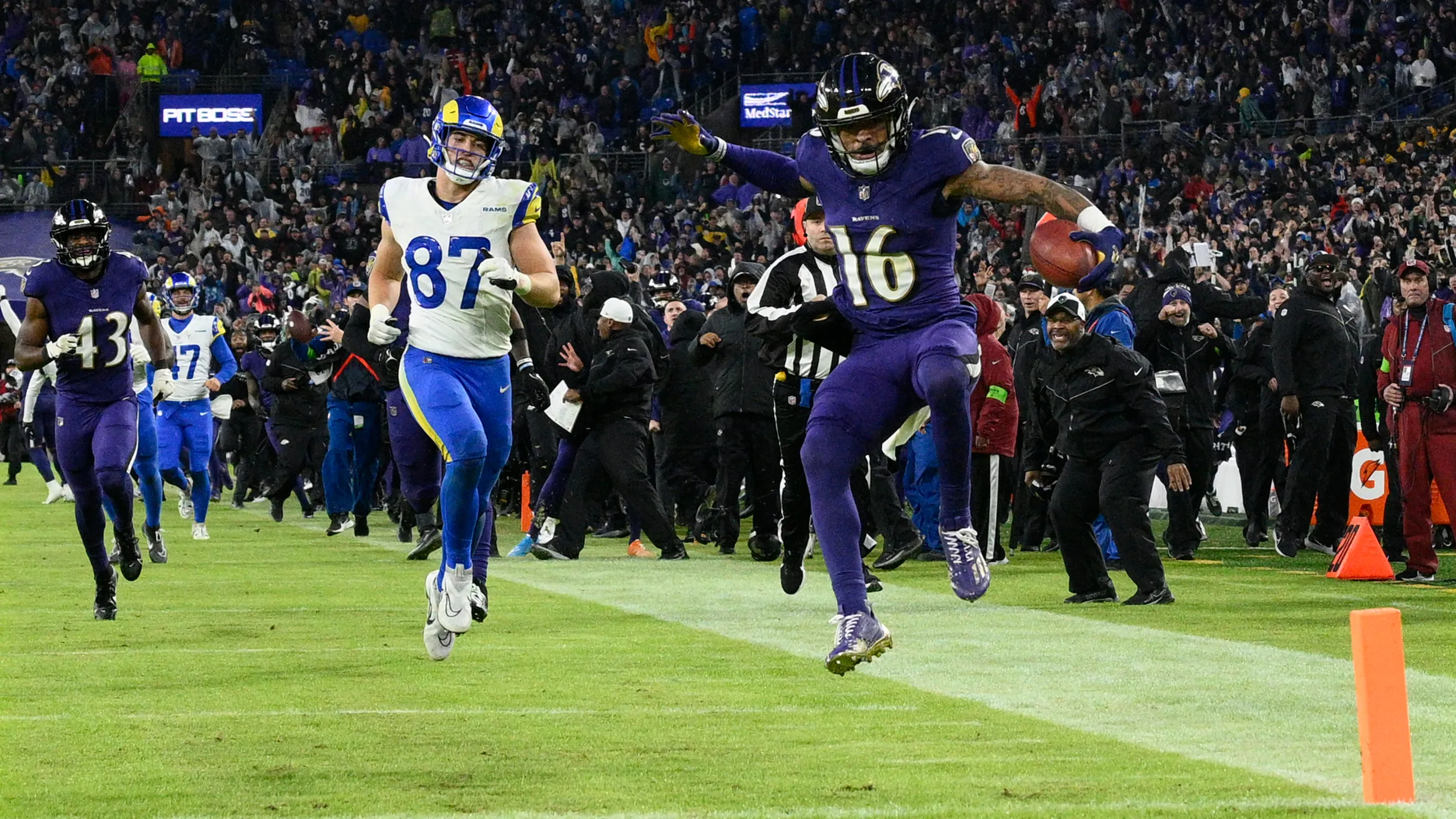 An NFL returner catching an overtime kickoff near the goal line as coverage players sprint downfield under bright stadium lights