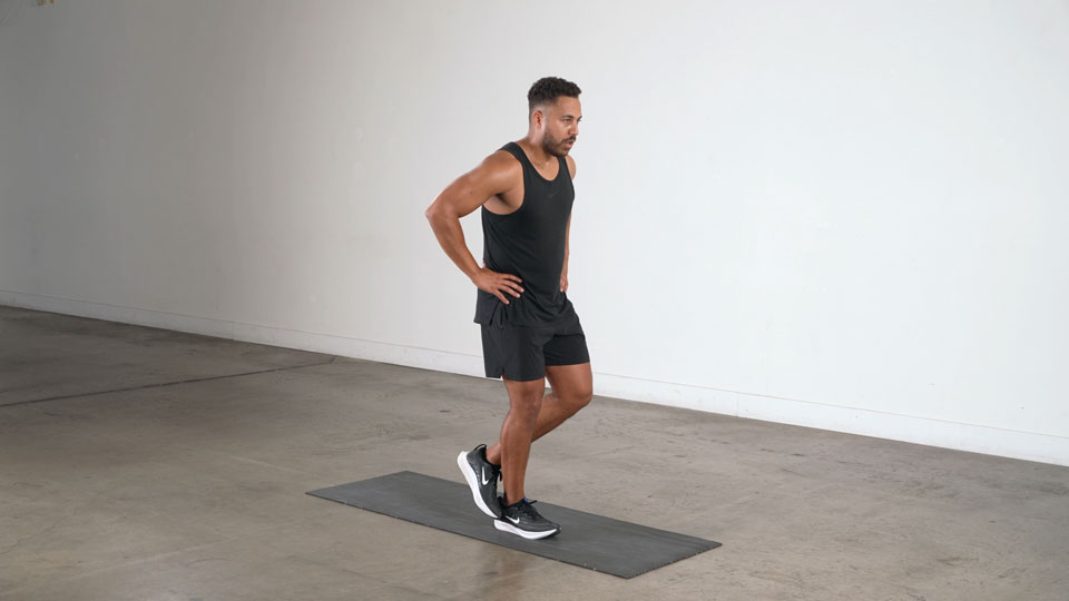 An athlete performing a single-leg calf raise on the edge of a step platform in a gym