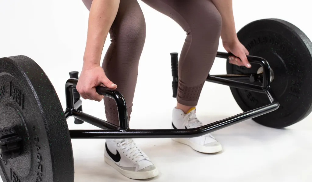 An athlete performing a trap bar deadlift in a gym with a neutral spine and braced core, focusing on powerful hip drive