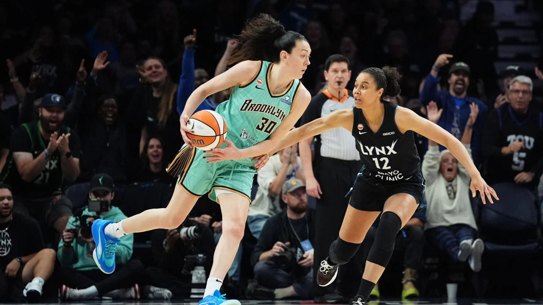 Breanna Stewart dribbling in a 2026 WNBA playoff game, defended tightly near the top of the key in a packed arena