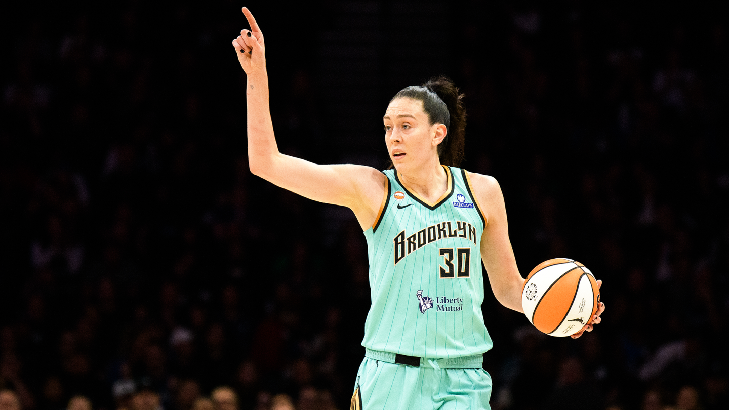 Breanna Stewart dribbling into the lane during a WNBA playoff game as defenders collapse around her under bright arena lights.