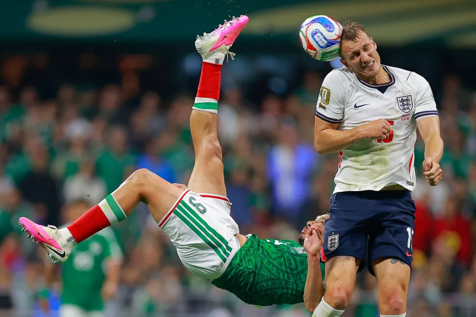 Dan Burn in an England kit tracking a forward during a 2026 World Cup match, eyes on the ball with the penalty area behind him