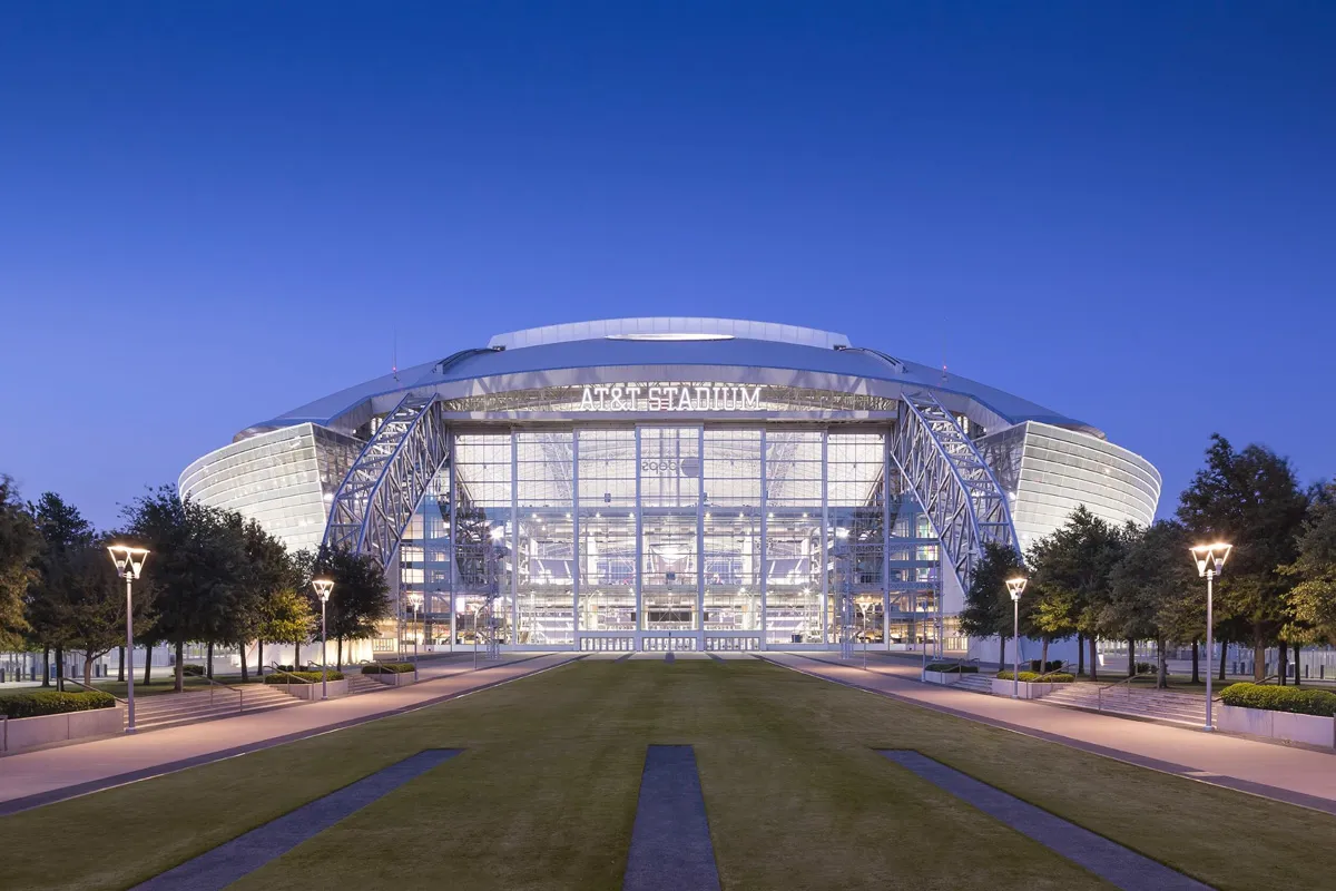 Game action inside AT&T Stadium during a Dallas Cowboys 2024 home game, with players lined up pre-snap and fans filling the stands