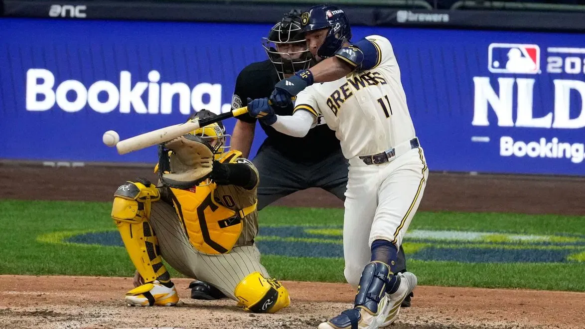 In-game action during an MLB postseason Division Series, with a pitcher delivering a pitch as the crowd stands behind home plate