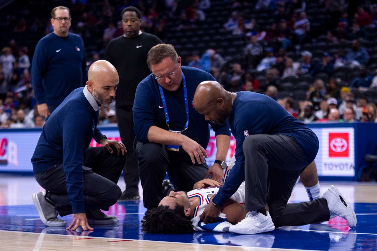 Jared McCain of the Philadelphia 76ers is helped off the court by staff during a preseason game against the Brooklyn Nets