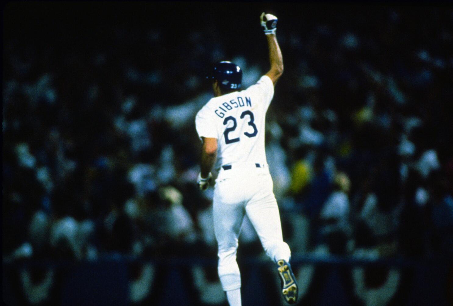 Kirk Gibson finishing a left-handed swing on a late-inning at-bat in a World Series game, crowd rising behind home plate
