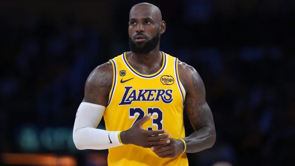 LeBron James in an NBA game, dribbling in transition with defenders retreating, in-arena action photo