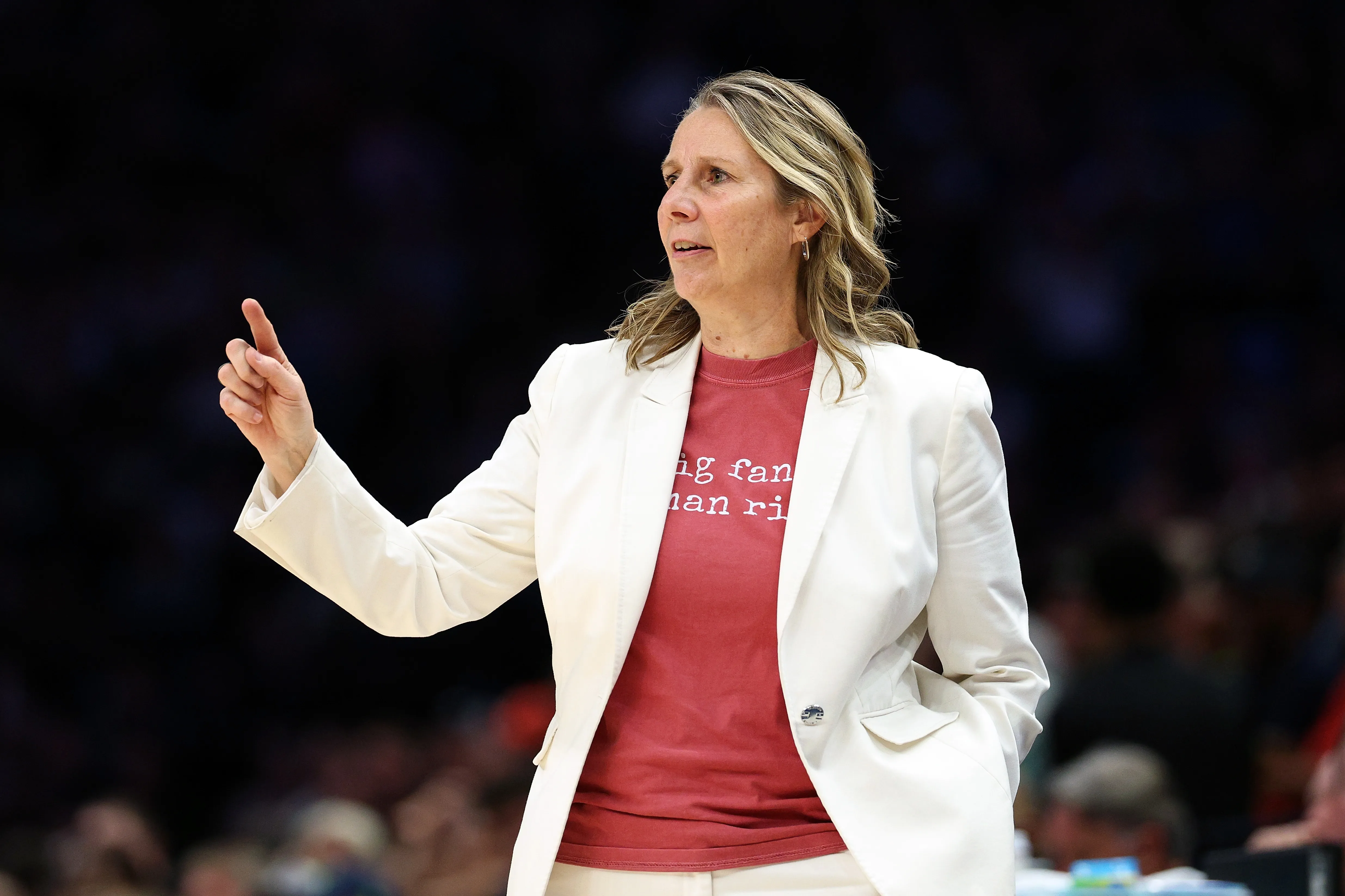 Lynx head coach Cheryl Reeve stands on the sideline during a WNBA playoff game, focused and watching the action.