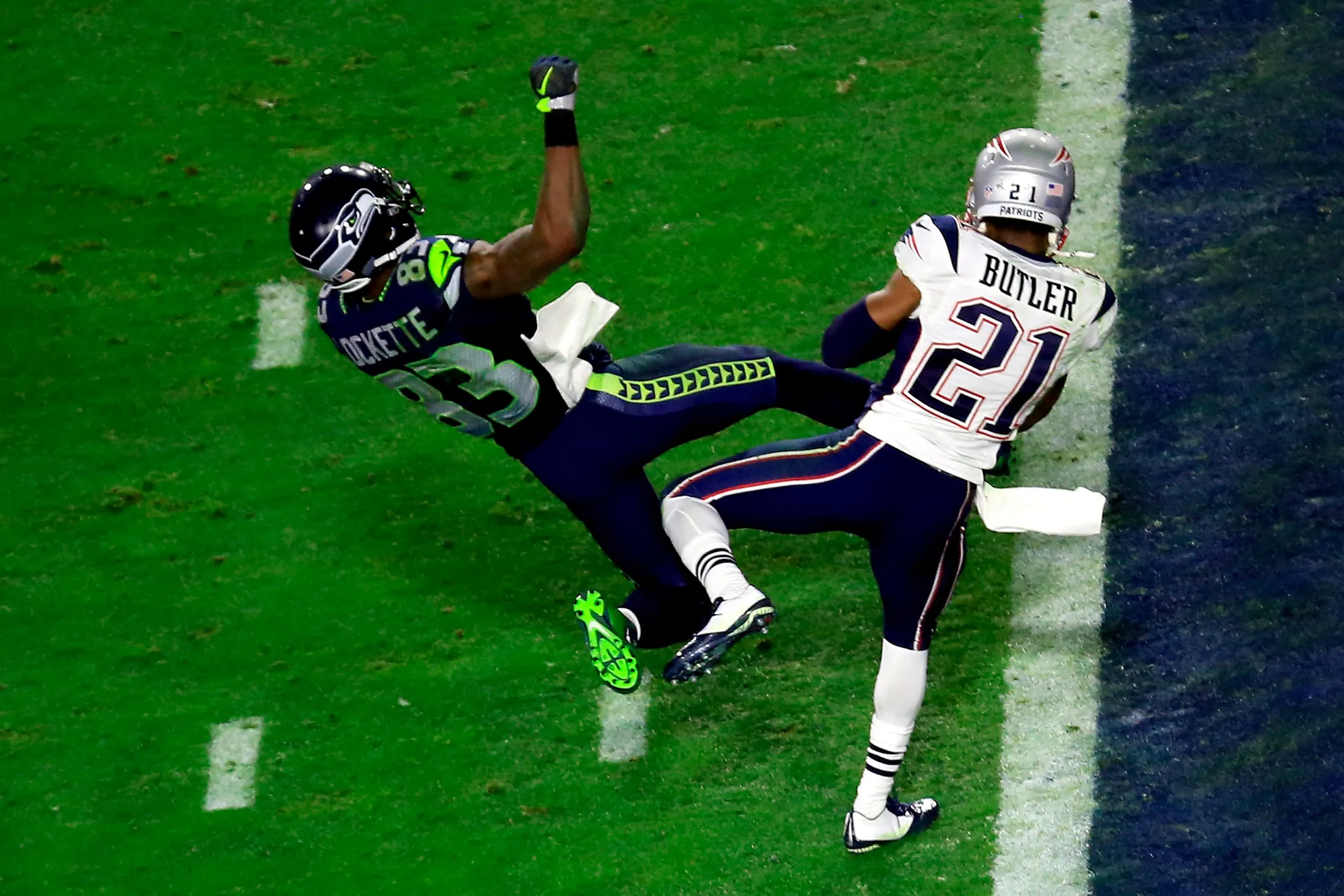 Malcolm Butler intercepting a goal-line pass in a Super Bowl as the receiver reaches forward and teammates react