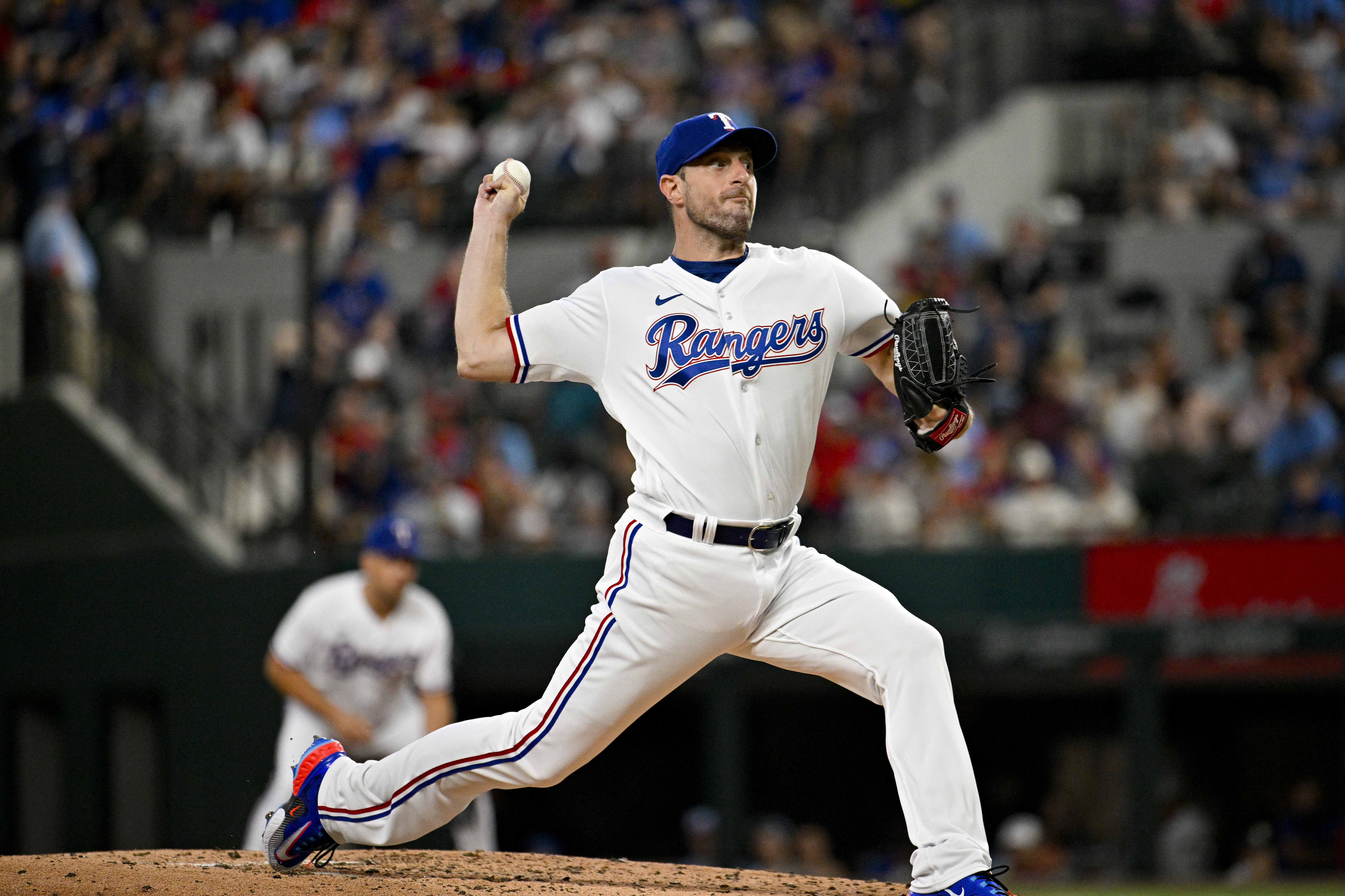 Max Scherzer in a Texas Rangers uniform pitching from the mound with the catcher set up low