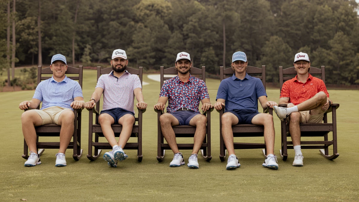 Members of Good Good Golf walk down a fairway during a filmed round, carrying golf bags and talking between shots.