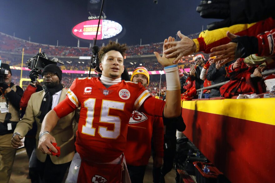 NFL players celebrating after a decisive overtime play in a playoff game with fans standing and cheering in the background