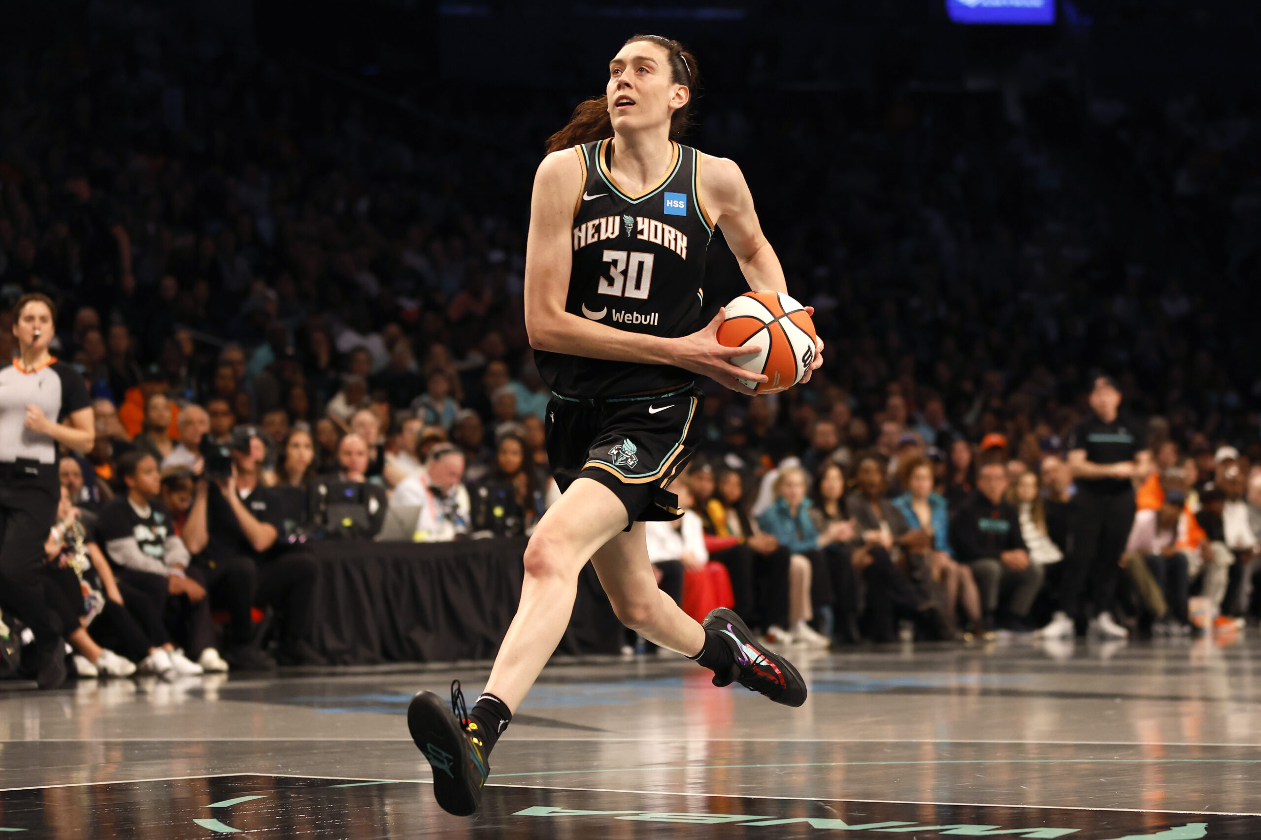 New York Liberty forward Breanna Stewart driving to the rim during a 2026 WNBA playoff game, with defenders collapsing in the paint in a packed arena