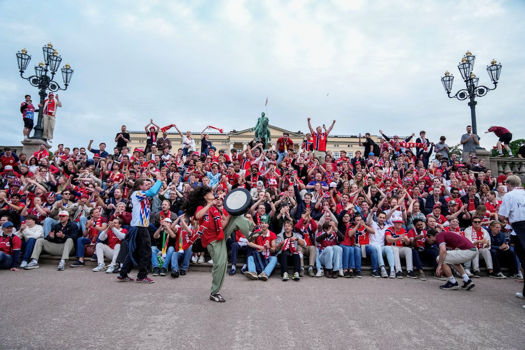Norway supporters in red waving flags and cheering in a 2026 World Cup stadium crowd
