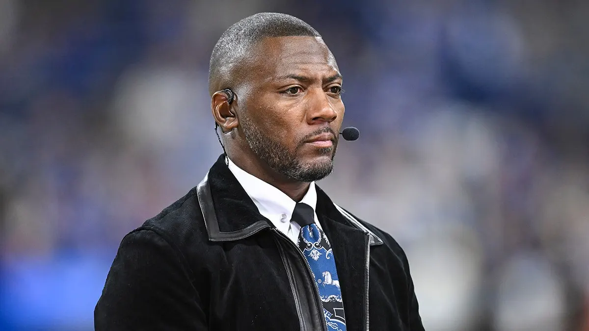 Ryan Clark on an ESPN studio set in a suit during a football segment, looking toward an off-camera panel
