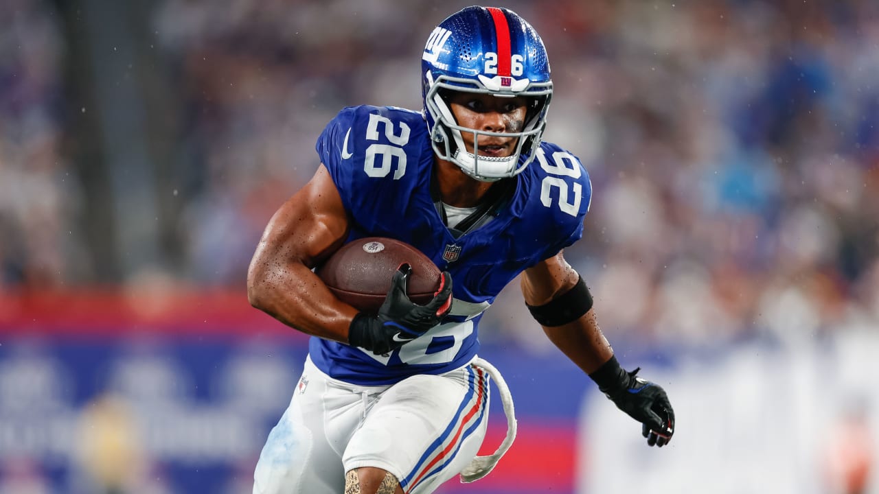 Saquon Barkley catching a pass in stride out of the backfield with a defender closing from the inside along the sideline during an NFL game