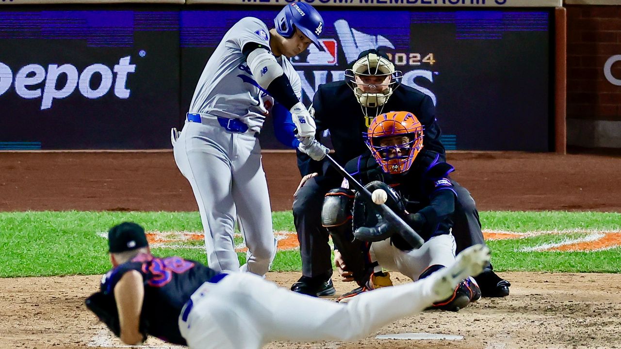 Shohei Ohtani finishing his swing after a home run against the New York Mets, with fans reacting behind home plate