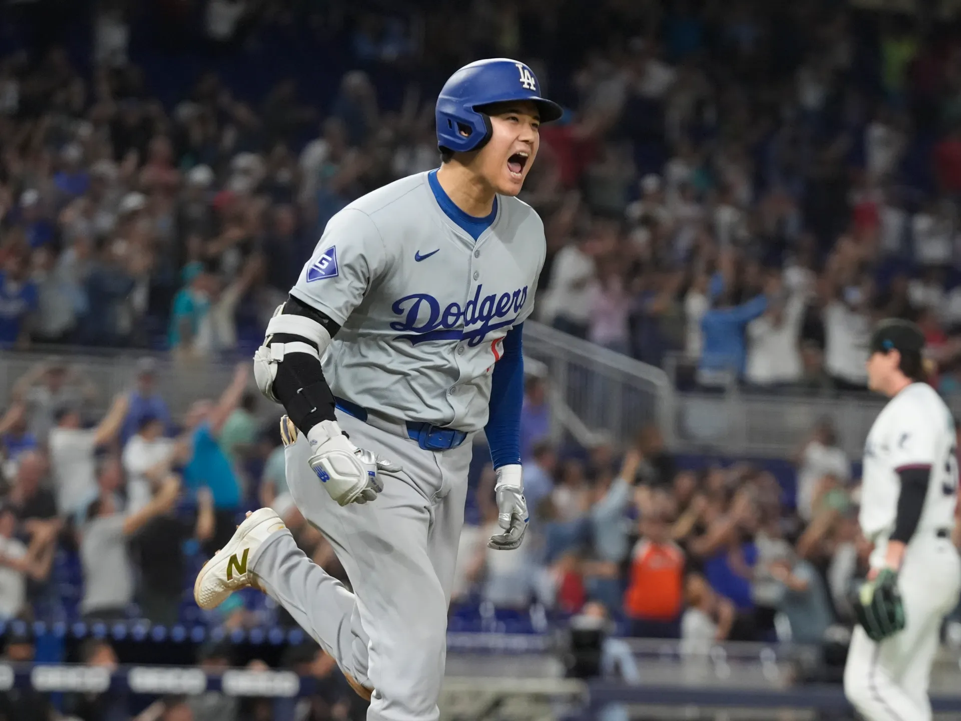 Shohei Ohtani in a Los Angeles Dodgers uniform taking a full swing in a regular-season MLB game, with the pitcher and catcher visible