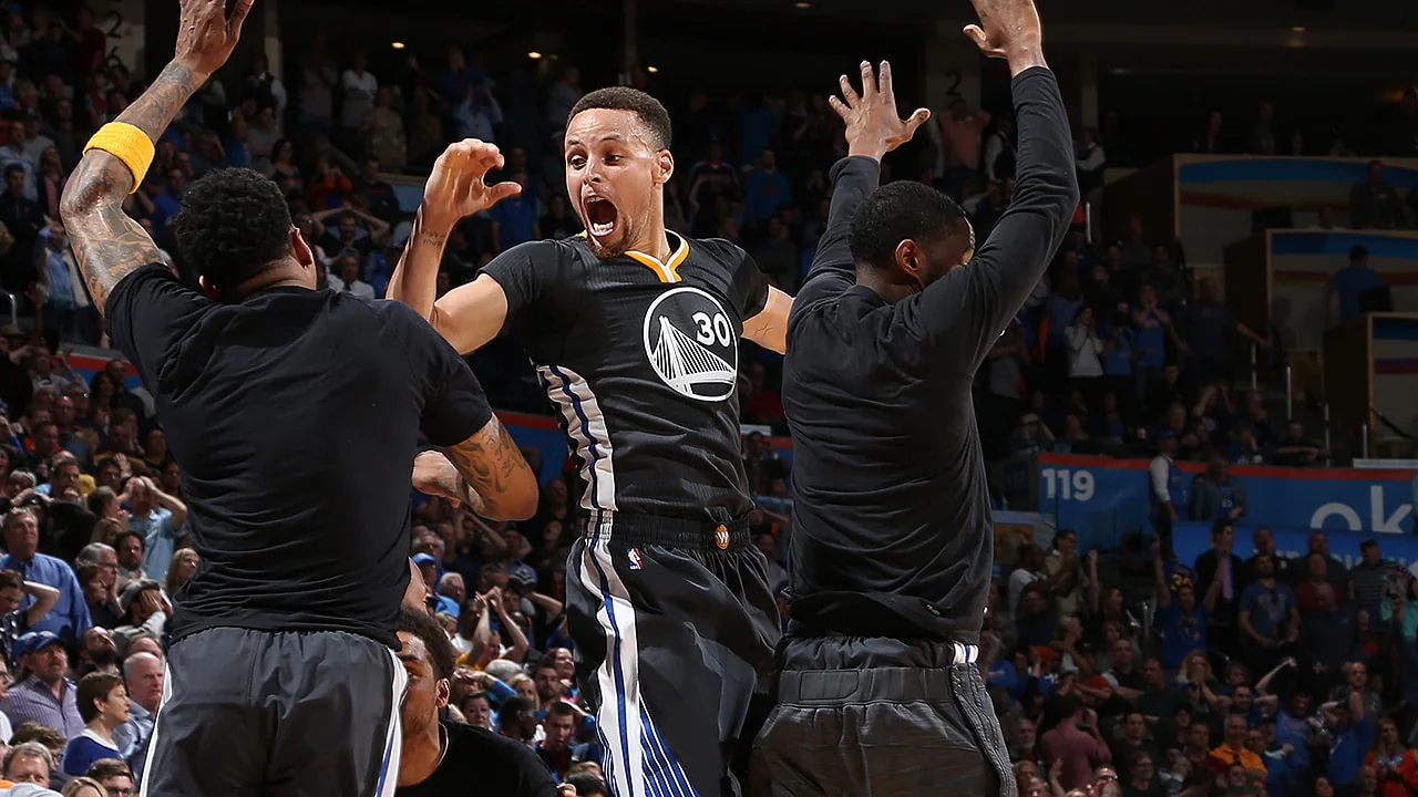 Stephen Curry launching a long three-pointer at the buzzer as defenders scramble during the Warriors vs Thunder game in 2016
