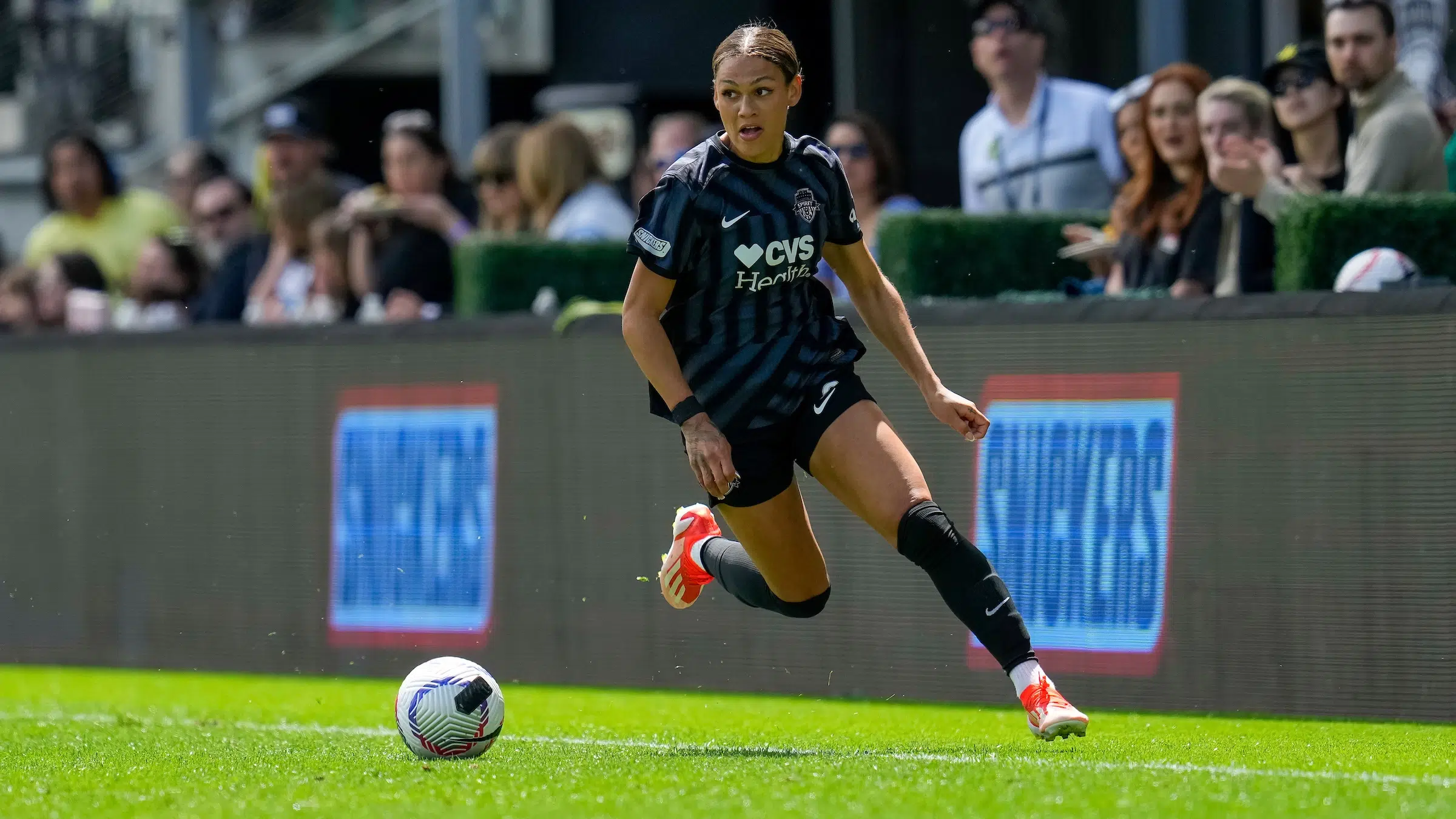 Trinity Rodman in a Washington Spirit match, wearing full kit on the field during live action as she accelerates toward the ball in a packed stadium