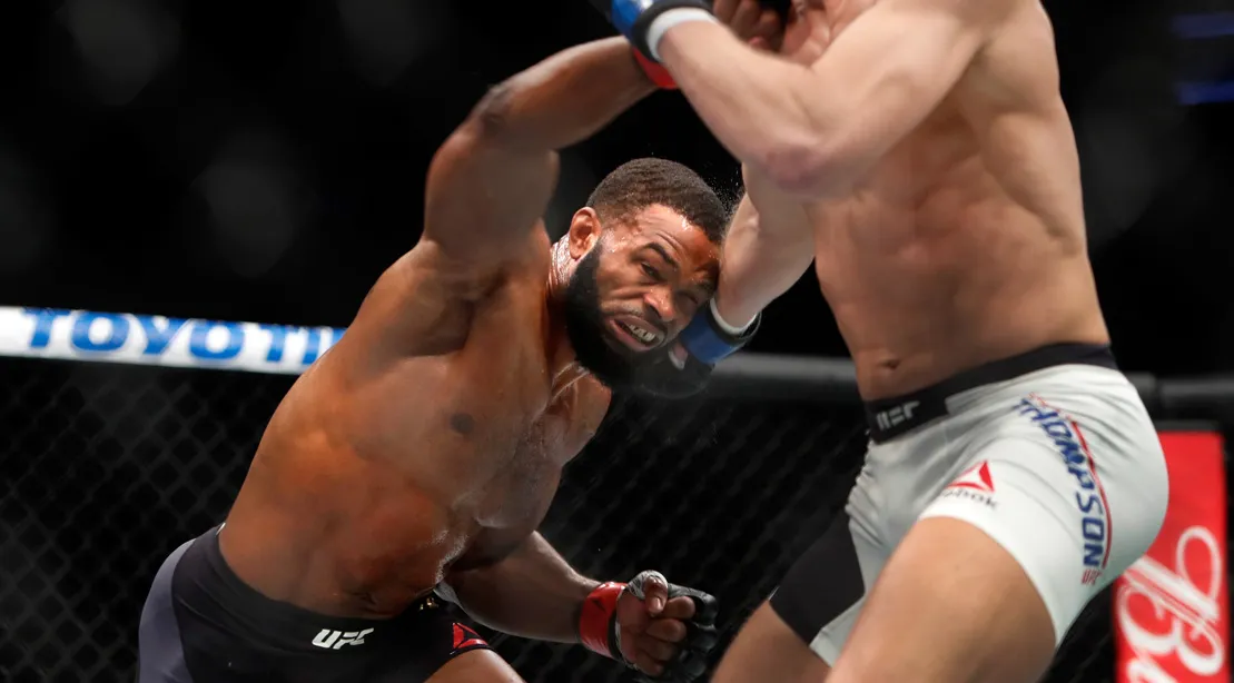 Two UFC fighters exchanging jabs in the center of the octagon while the referee watches closely