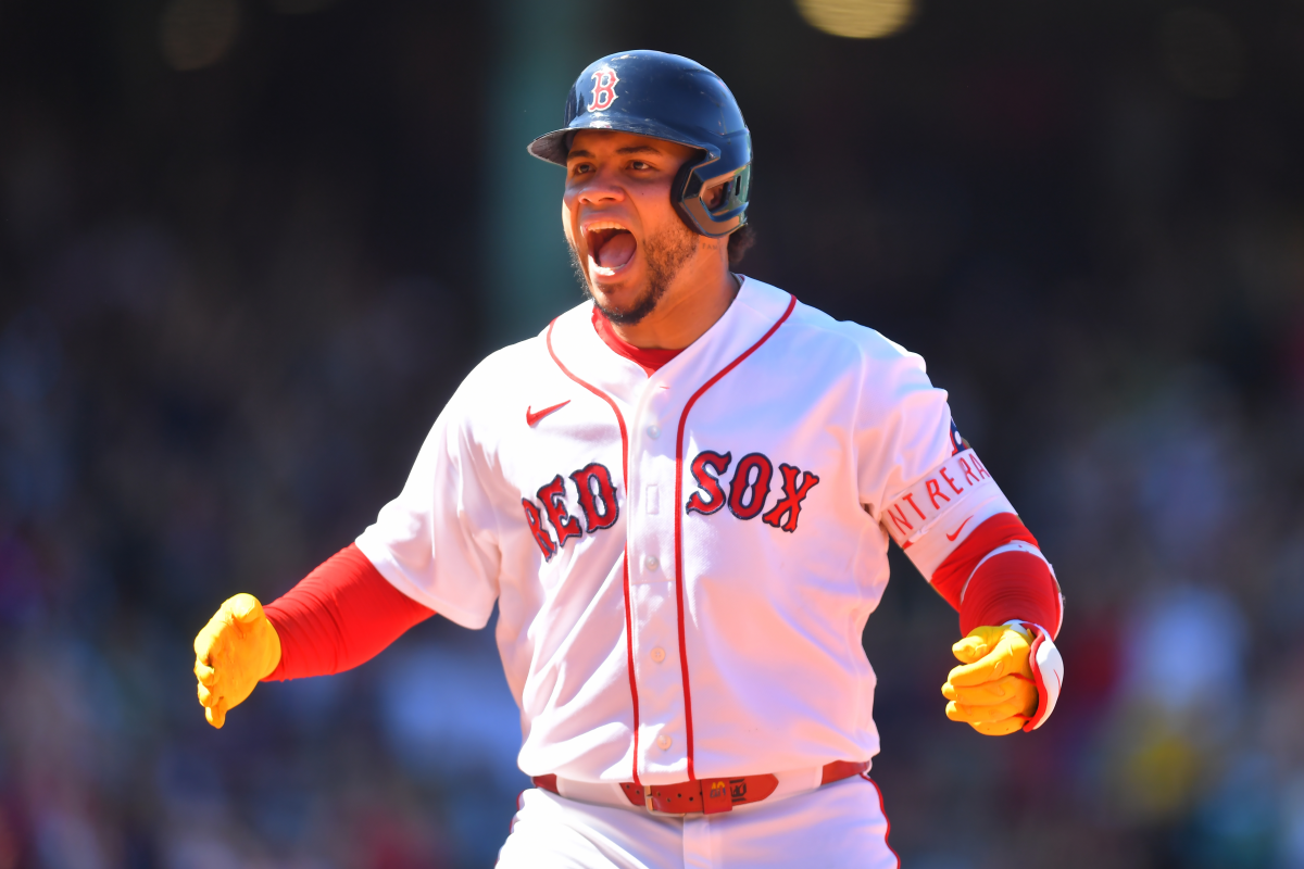 Wilson Contreras in a Boston Red Sox uniform reacting intensely near the dugout after a big hit, with teammates visible behind him